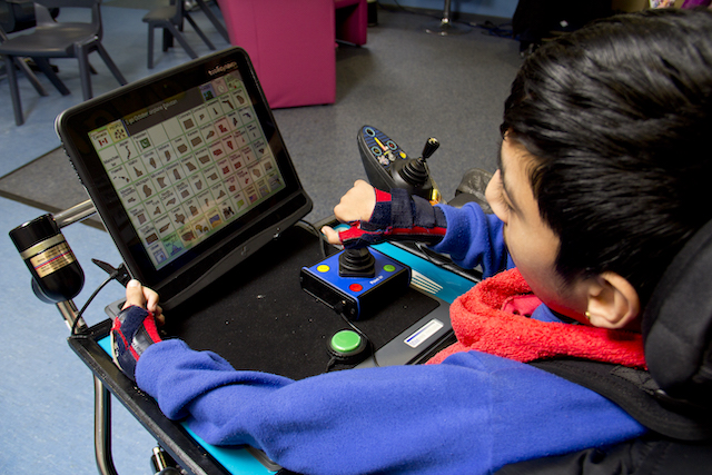 A young person accessing a communication aid using a joystick